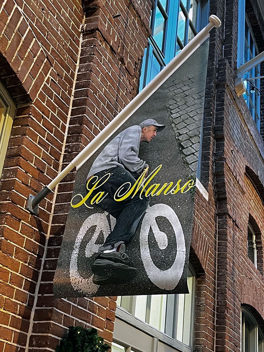 Flag outside a brick building shows a person riding a bicycle on a textured surface, 