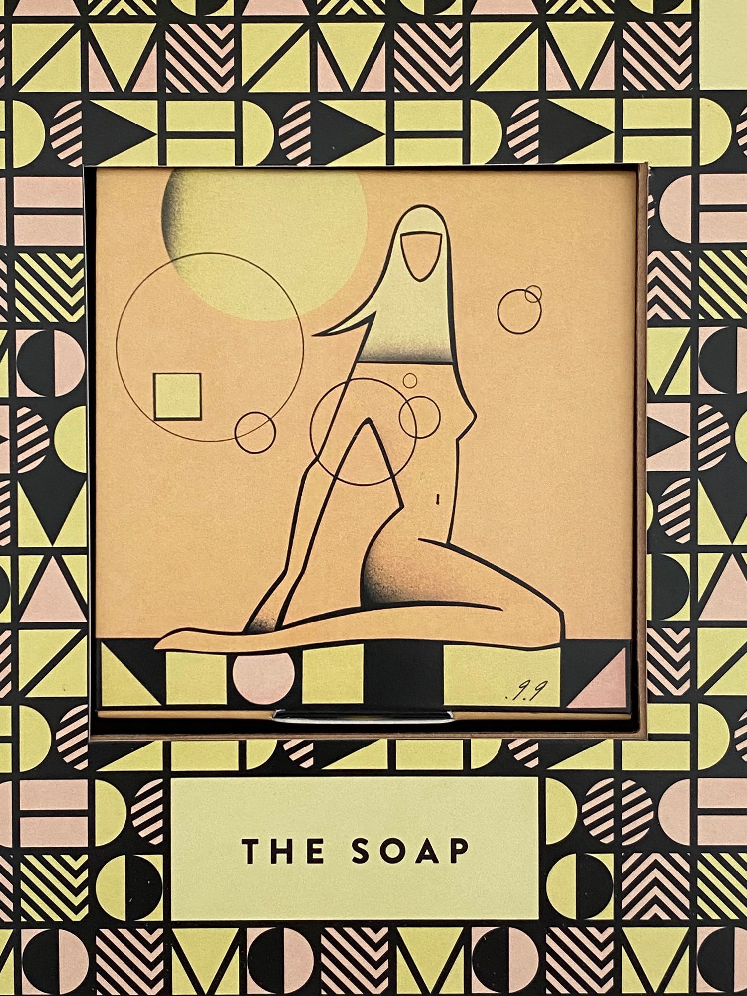 Soap packaging with art deco design and a stylized seated figure. Yellow, black, and pink colors.