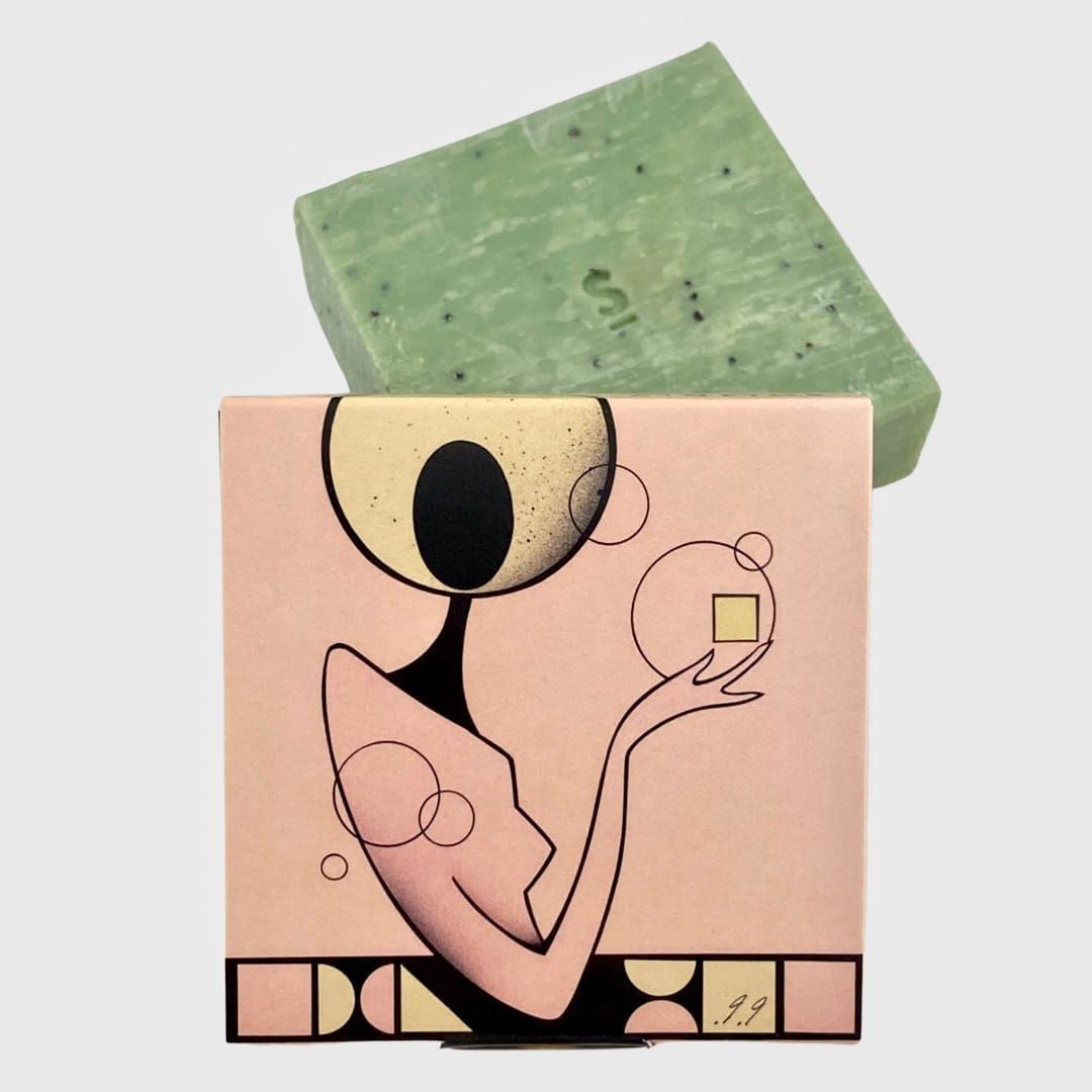 Boxed soap with art of a person holding a square. Soap is green. Box is peach and pink.