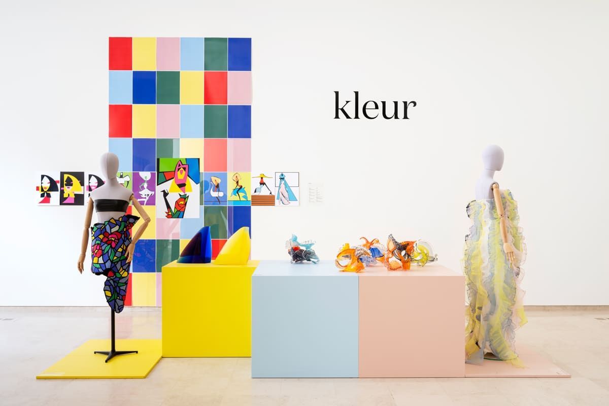 Colorful art installation with mannequins wearing patterned garments. Cubes, colorful squares, the word
