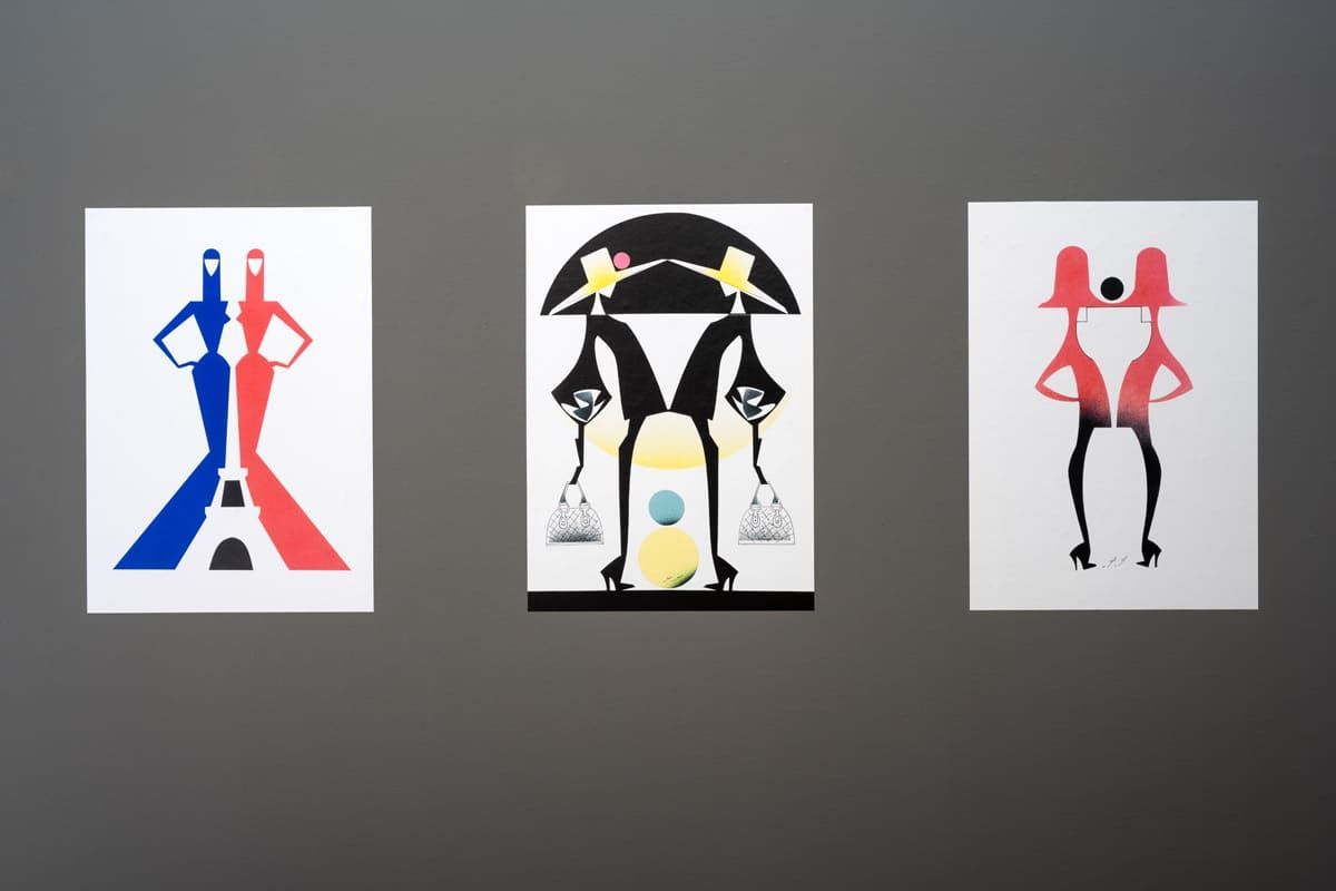 Three art prints on a gray wall. Each features abstract figures in red, blue, black, and yellow.