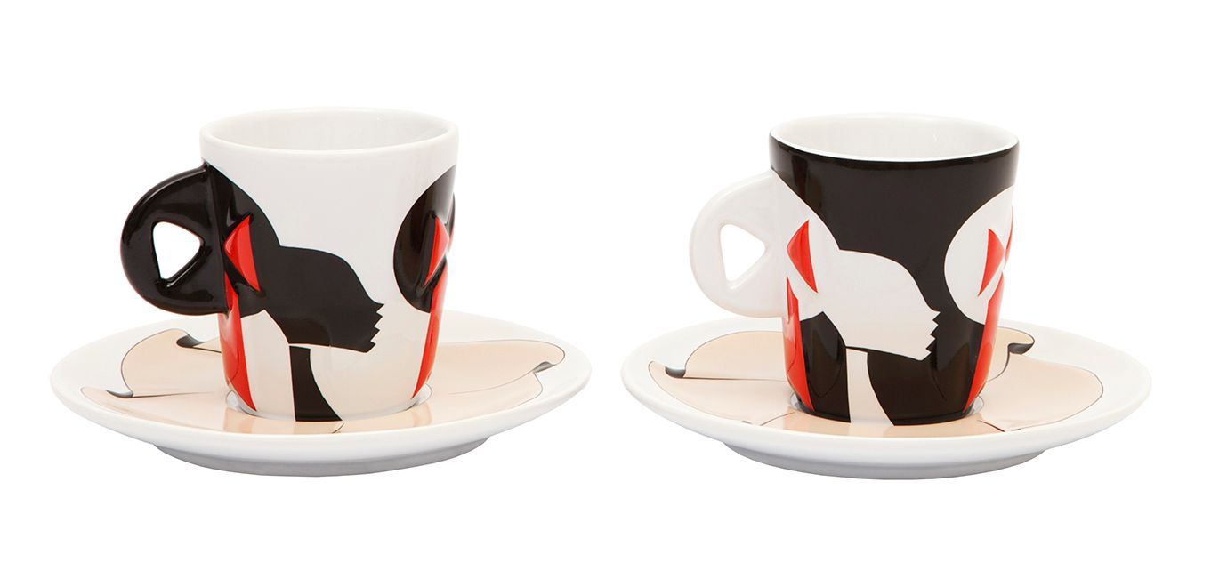 Two espresso cups with saucers, white with black and red abstract design. One cup's handle is black. The other's is white.