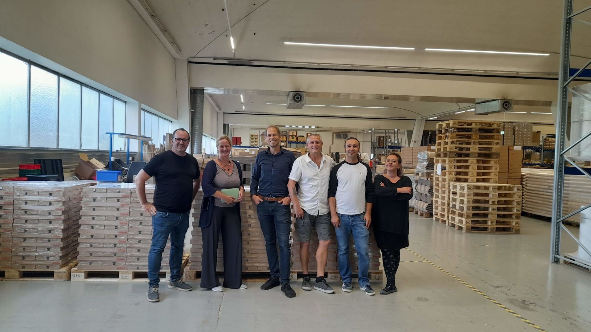 Eine Gruppe von Menschen posiert in einem Lagerhaus für ein Foto.