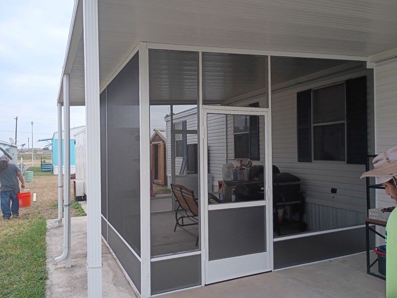 Screened porch with white trim and glass door, furnished with chairs and a grill on a cloudy day