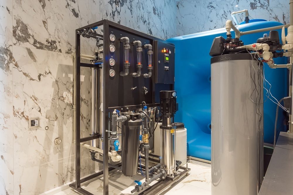 Industrial water treatment system with metal tanks, filters, and blue panels in a utility room