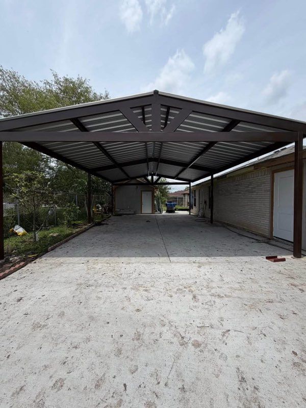 Covered driveway with a metal carport and concrete floor, viewed from the entrance