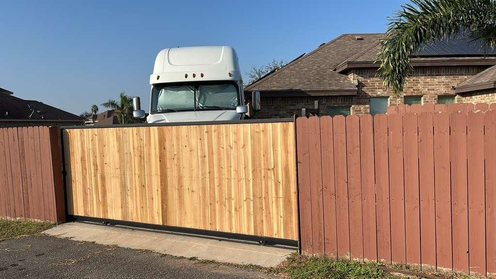 White truck behind a wooden fence in front of a house with a tiled roof
