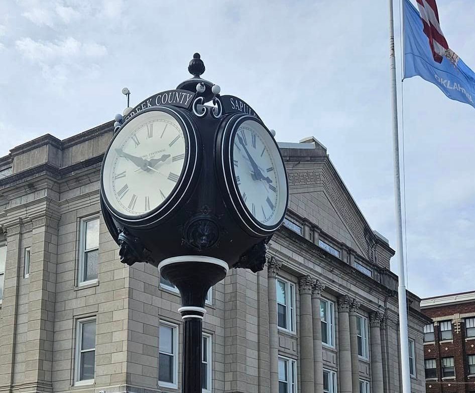 A clock on a pole in front of a building