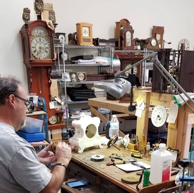 A man is working on a clock in a parking lot
