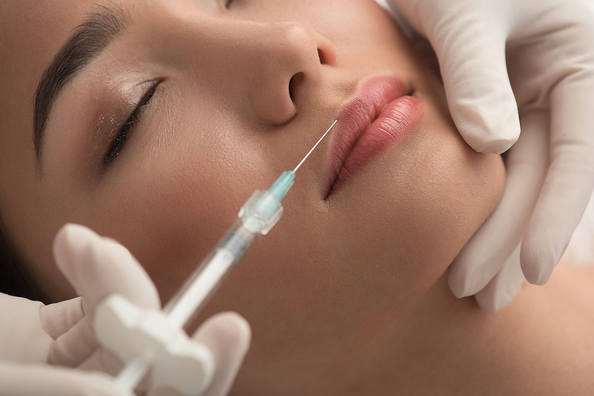 Eine Frau bekommt eine Botox-Injektion in die Lippe.