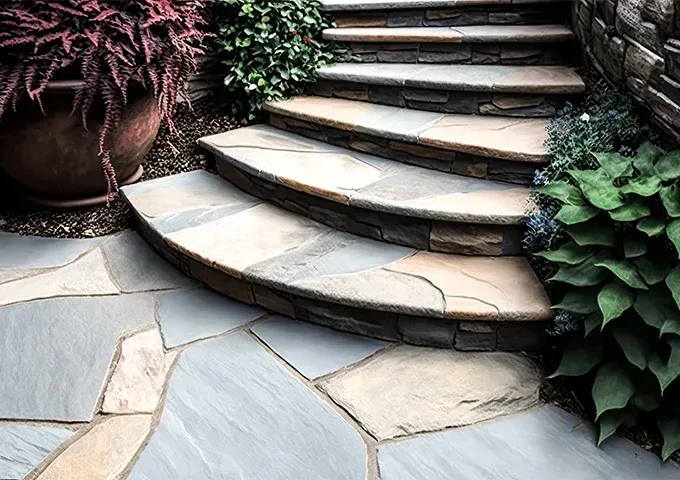 Stone steps curve upward outdoors, surrounded by lush potted plants and a natural flagstone patio.