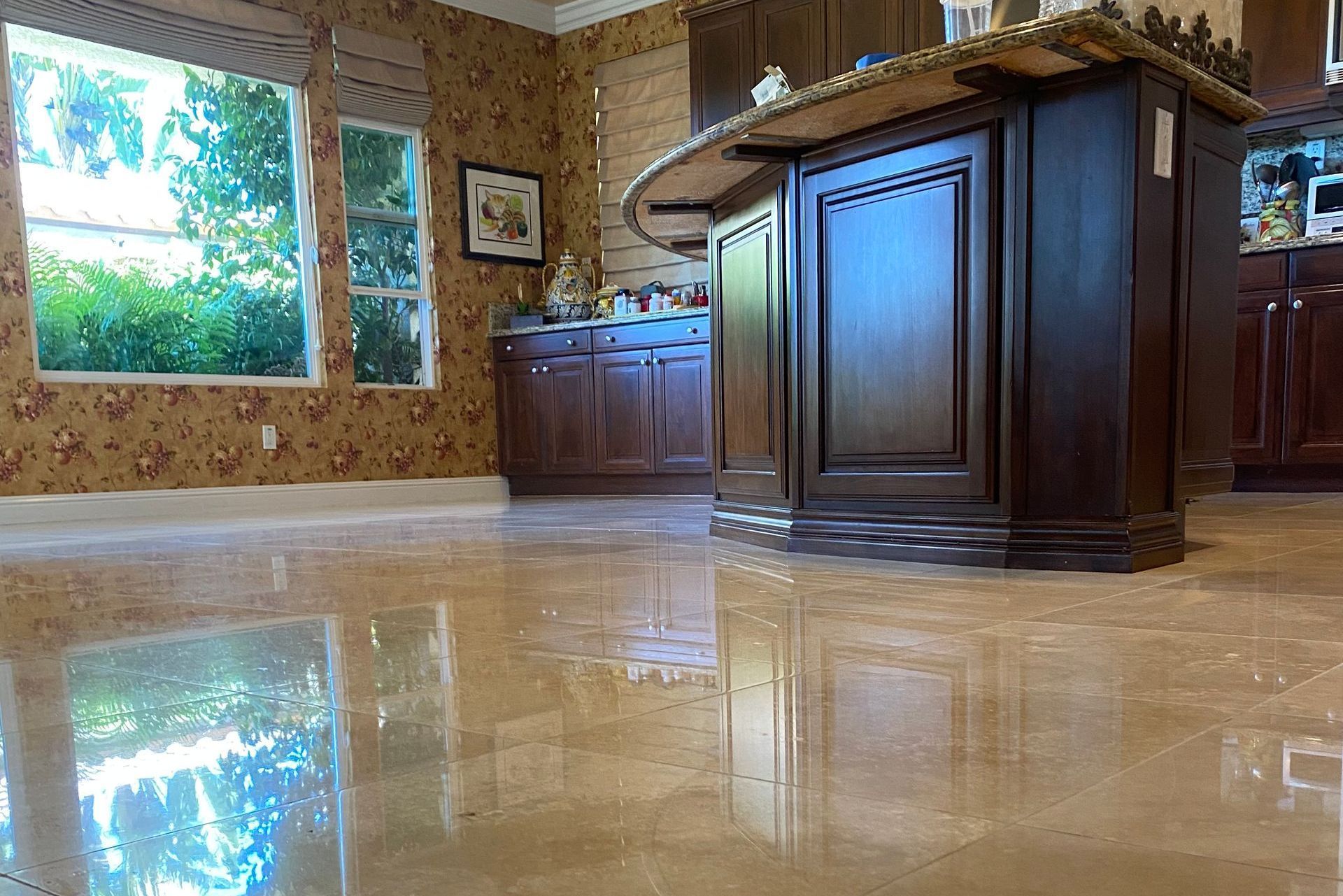 A polished, tan marble floor reflects a kitchen with dark wood cabinets and floral wallpaper.
