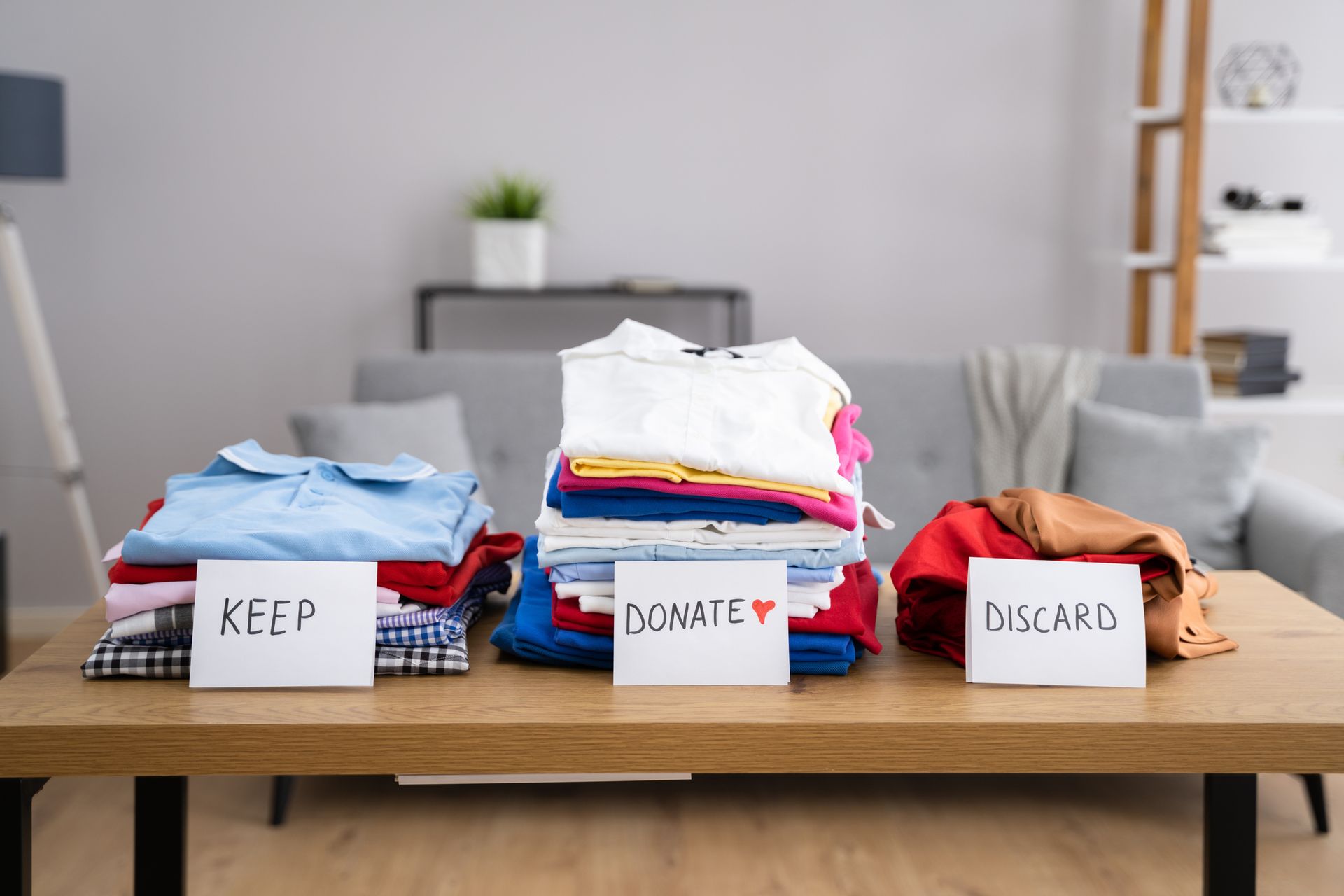 A wooden table with three stacks of clothes on it.