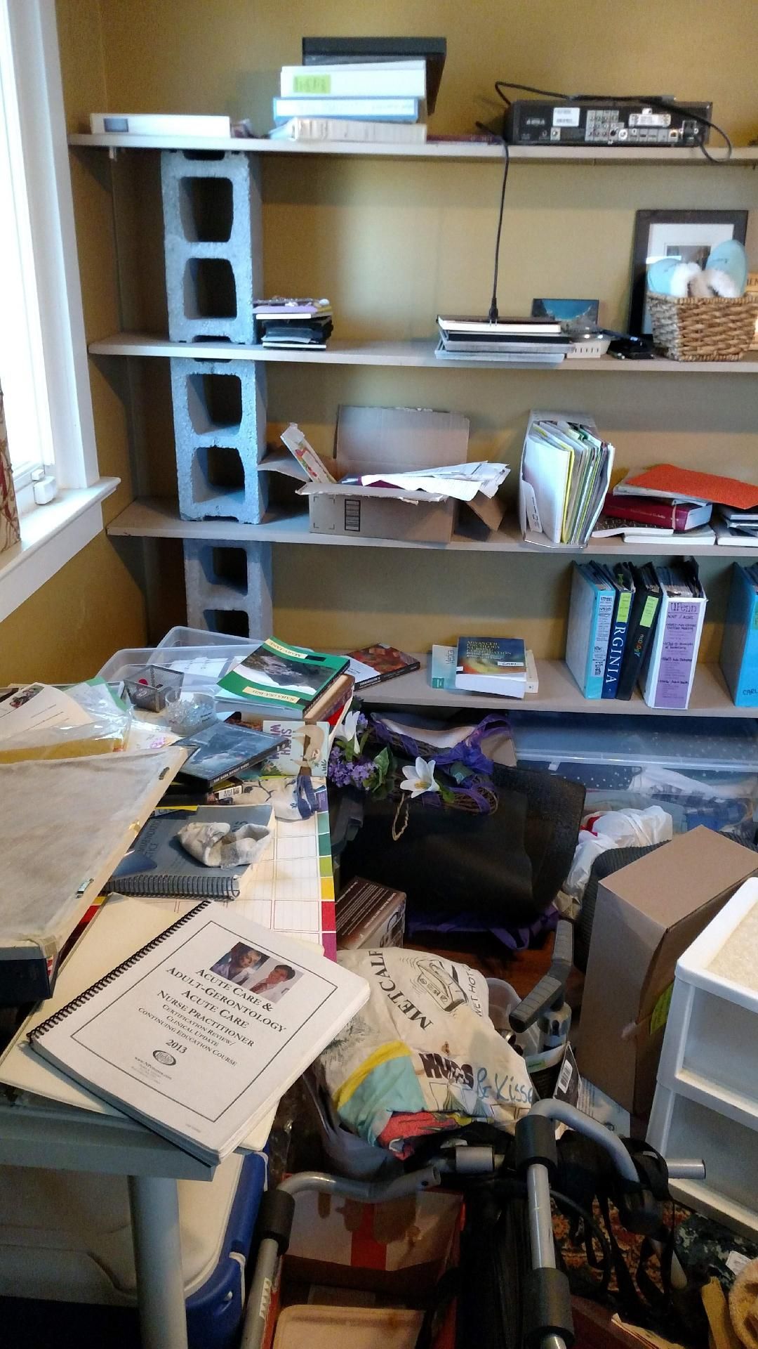 A messy room with a desk , shelves , and a window.