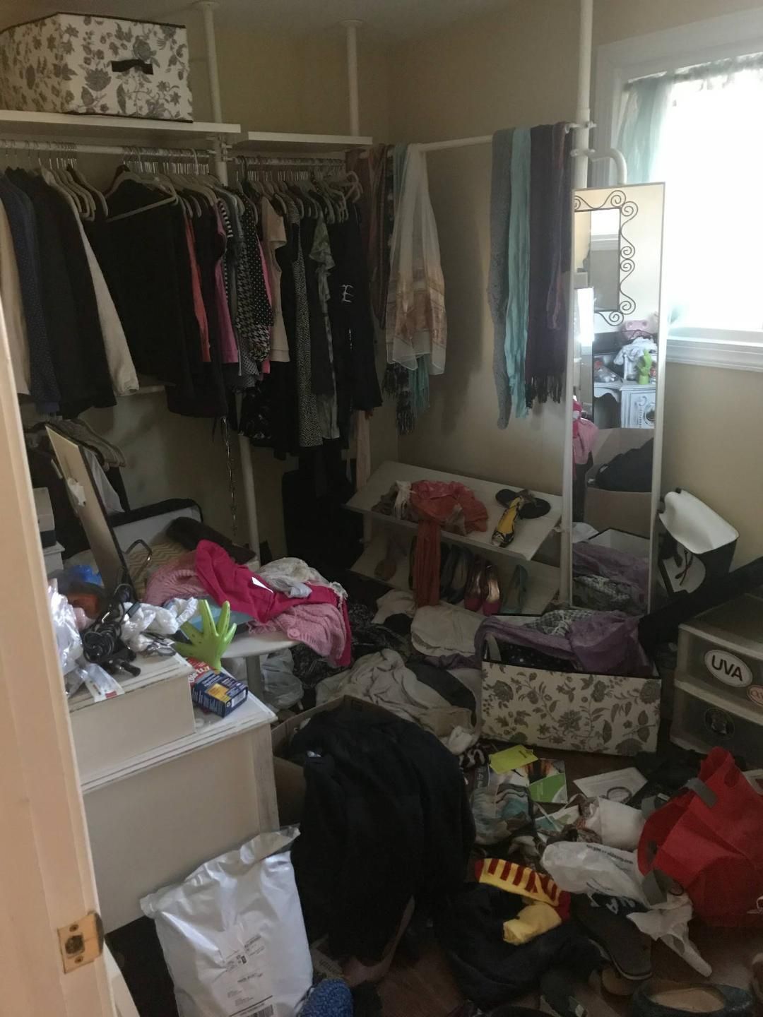 A messy closet with a lot of clothes and a mirror.