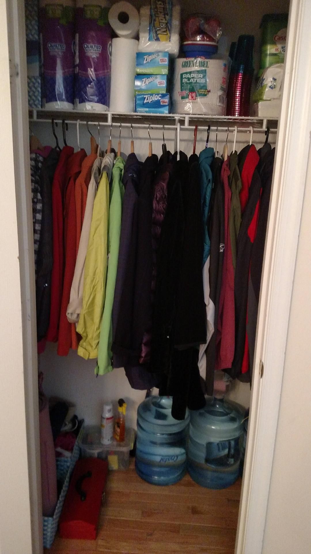A closet filled with clothes and toilet paper.