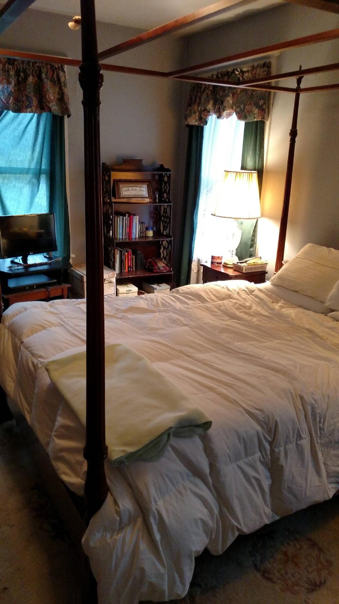 A bedroom with a four poster bed and a bookshelf.