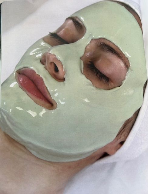 A woman with a tattoo on her neck is getting a facial massage