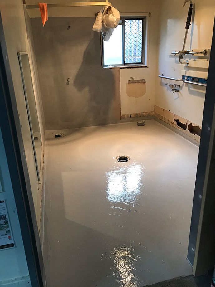 Bathroom with wet, light gray floor; walls in progress; window.