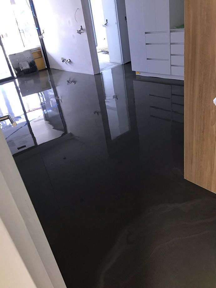 Dark, wet flooring reflecting interior features, including cabinets and white walls.