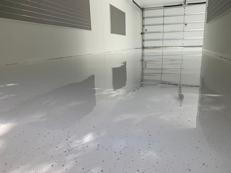 Bright white epoxy garage floor reflecting light, with a closed garage door in the background.