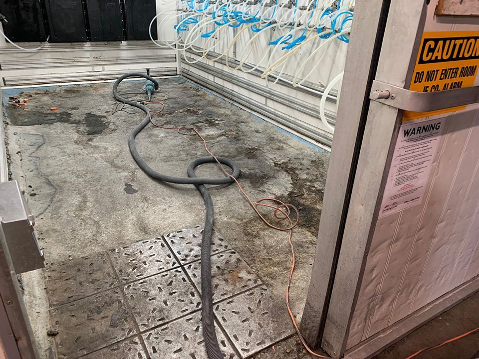 Floor with hoses and equipment; caution sign on right.