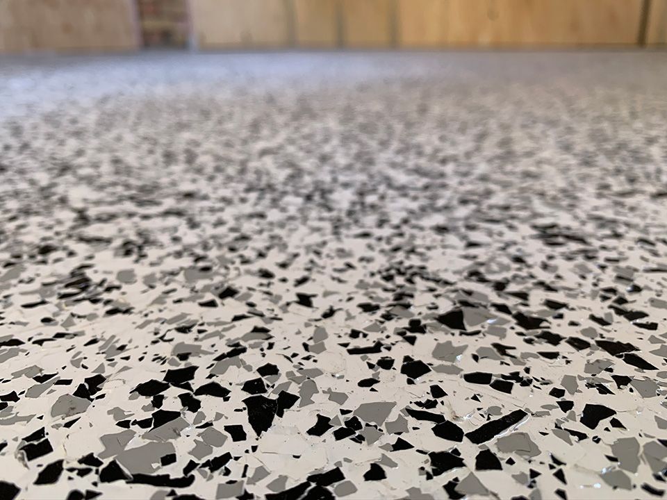 Close-up of a speckled floor with black, gray, and white chips. The floor appears smooth and reflective.