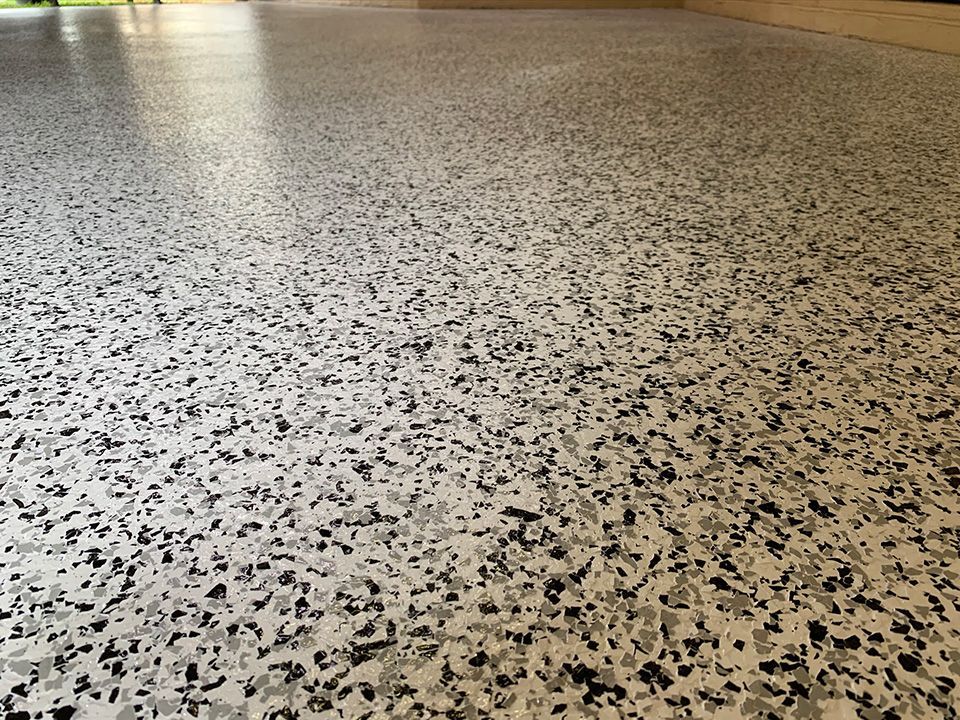 Epoxy-coated garage floor with gray, black, and white flakes for a textured, durable surface.