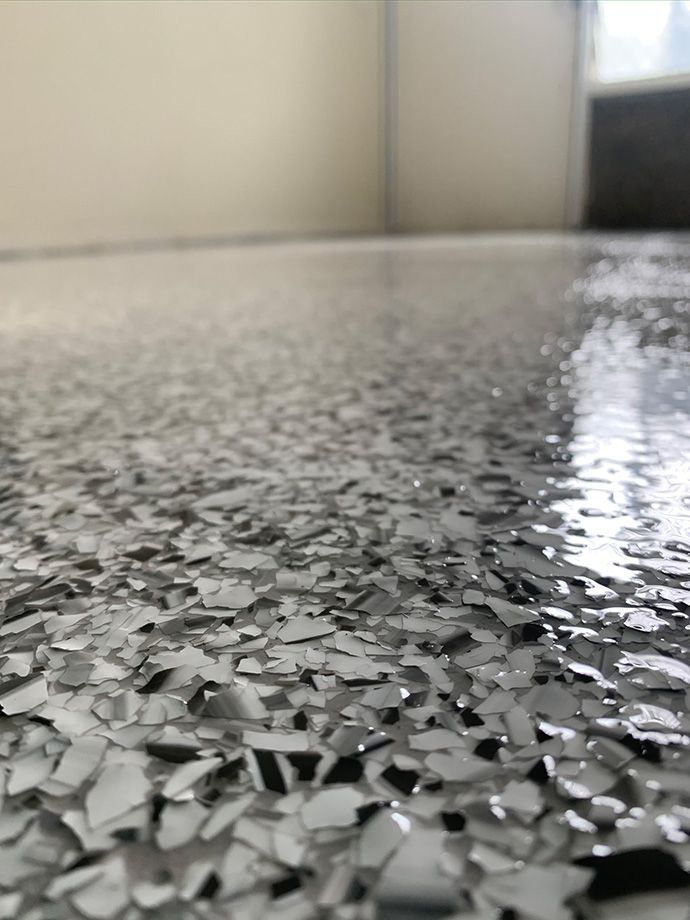 Close-up of a speckled, glossy gray and white epoxy garage floor.