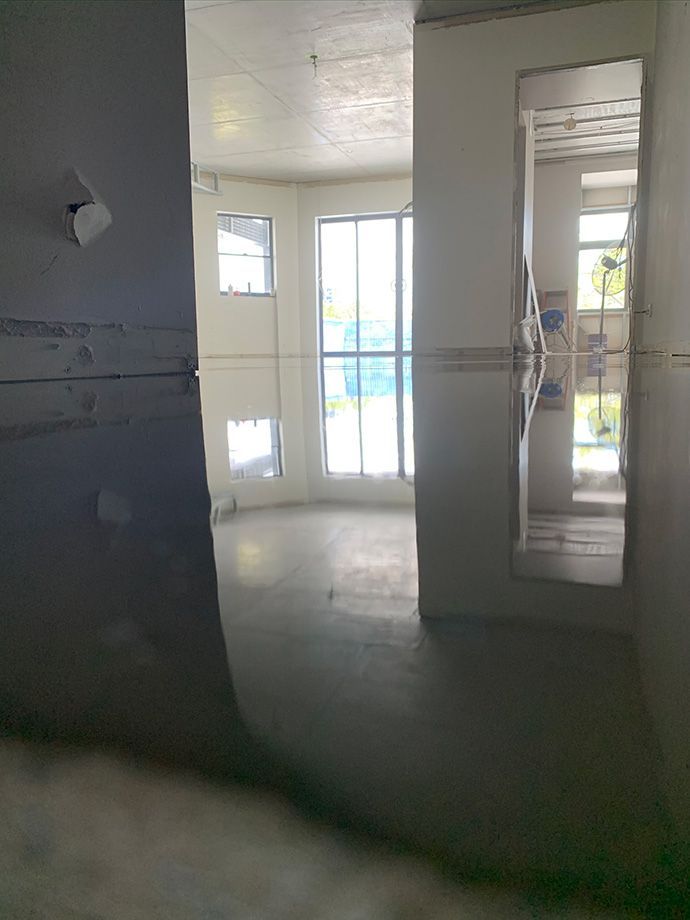 Empty interior rooms with large windows and a concrete floor.