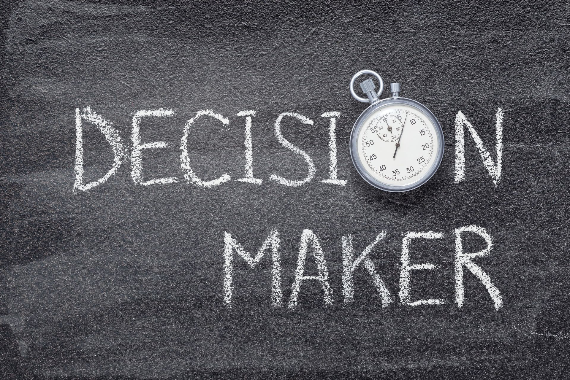 'Decision Maker' written in white chalk on a blackboard with a small stopwatch icon.
