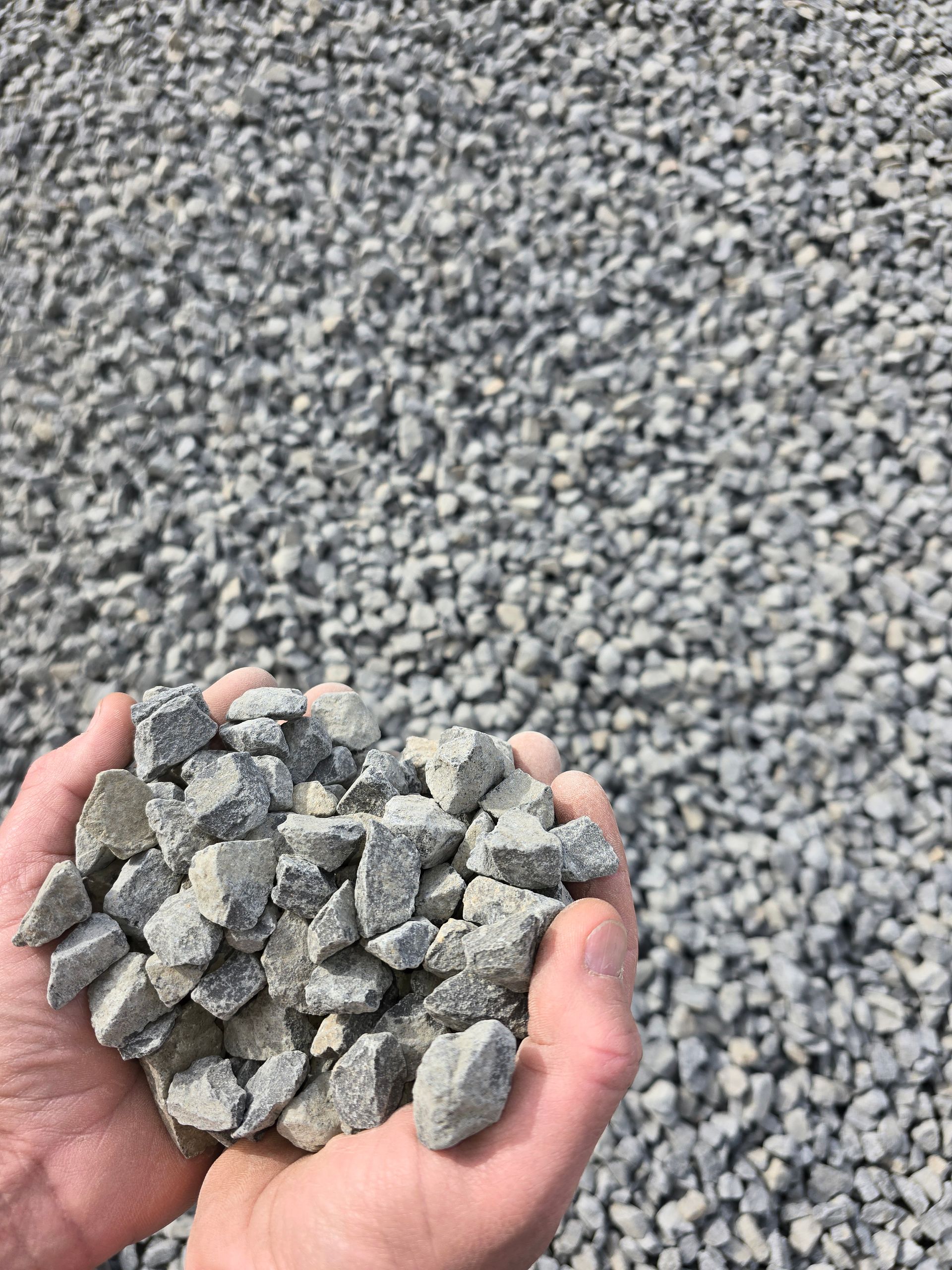 Hands Holding a Pile of Grey Gravel — BVN Landscape and Concrete Supplies in Vincentia, NSW