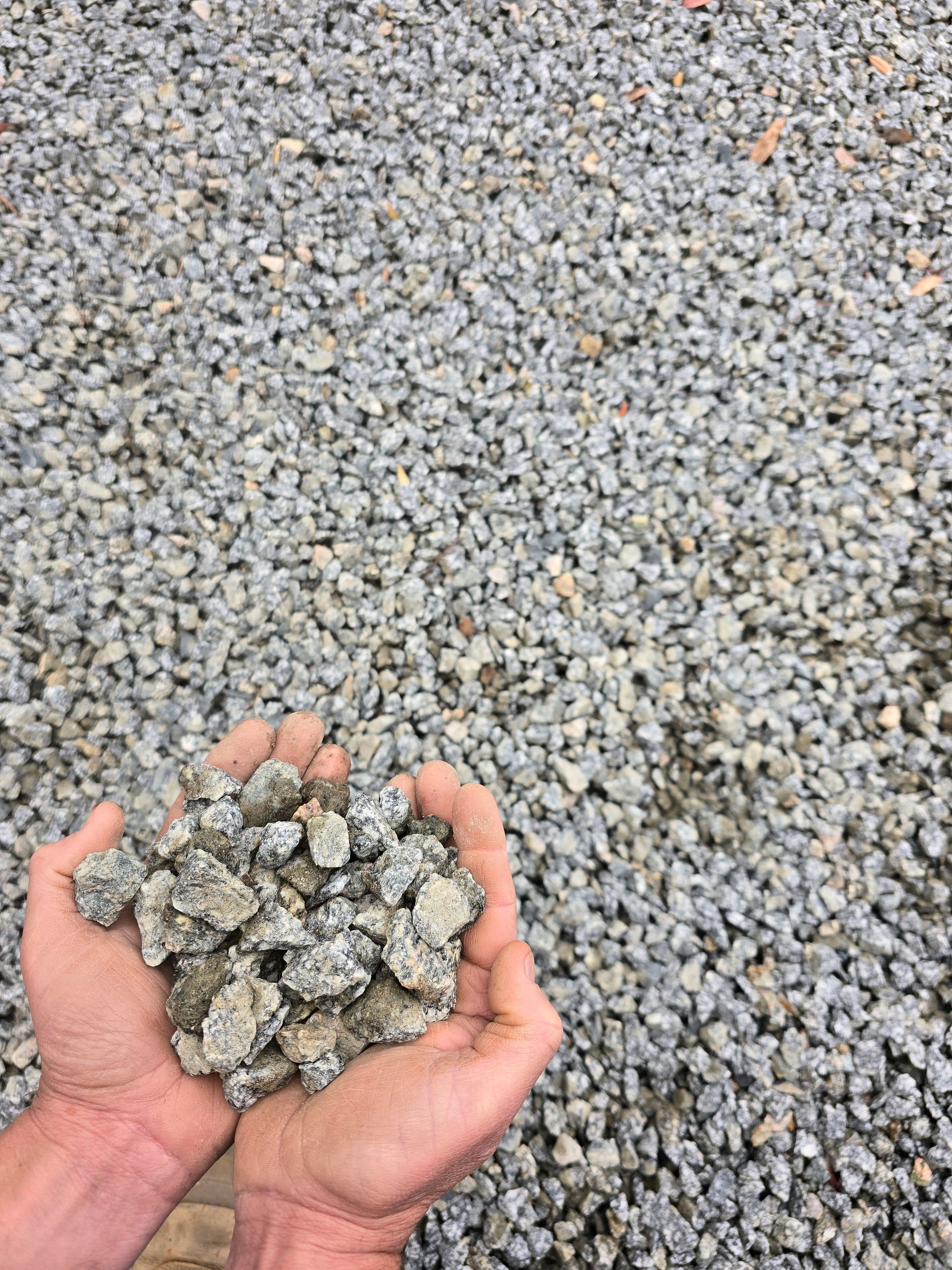 Hands Holding a Pile of Grey Gravel — BVN Landscape and Concrete Supplies in St Georges Basin, NSW