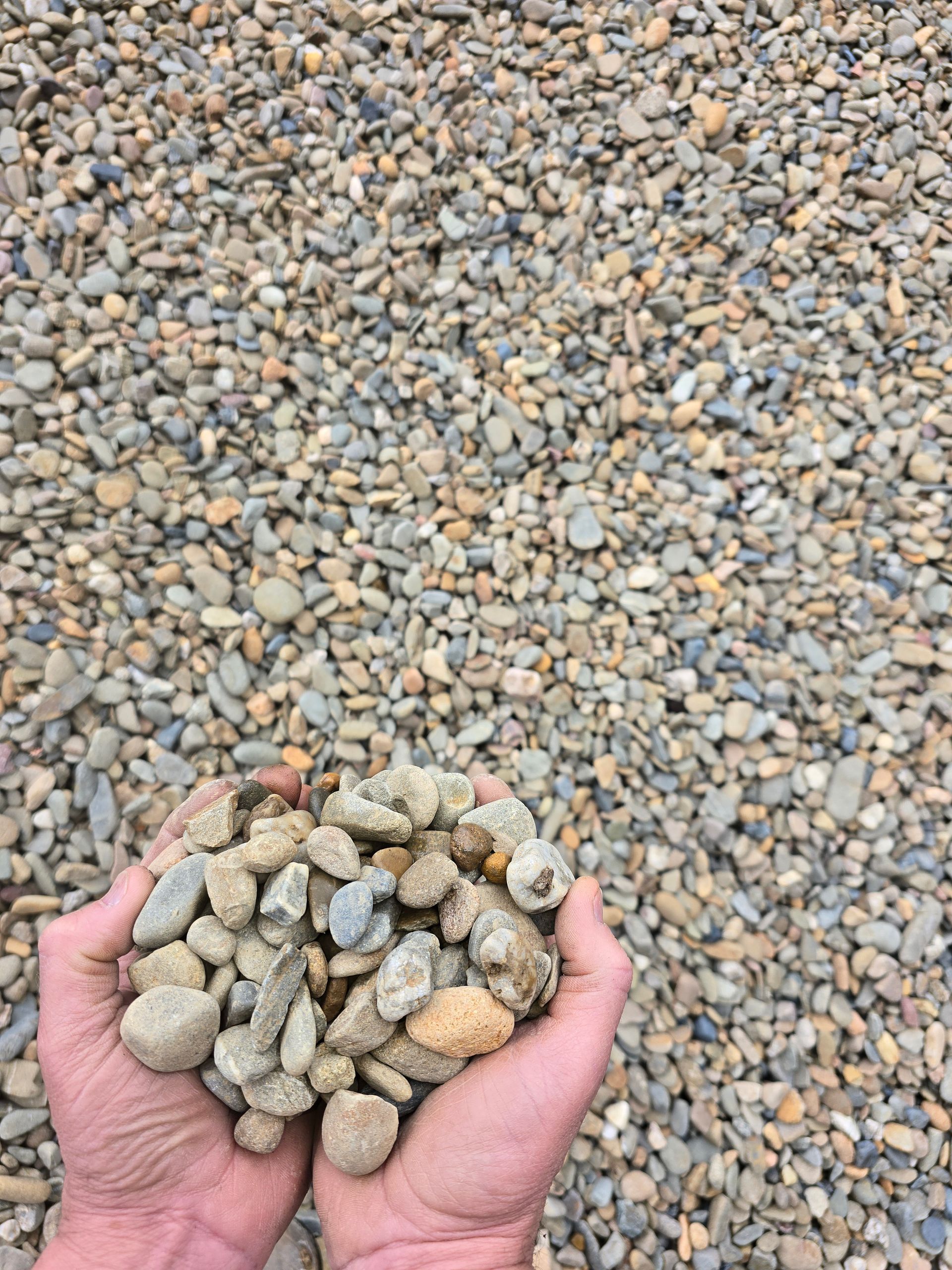 Hands Holding a Pile of Smooth, Multi-coloured River Rocks — BVN Landscape and Concrete Supplies in St Georges Basin, NSW