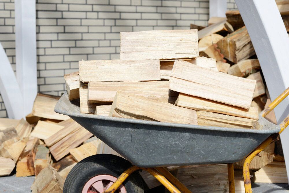 Wheelbarrow Piled With Stacked Firewood in Front of a Brick Wall — BVN Landscape and Concrete Supplies in Huskisson, NSW