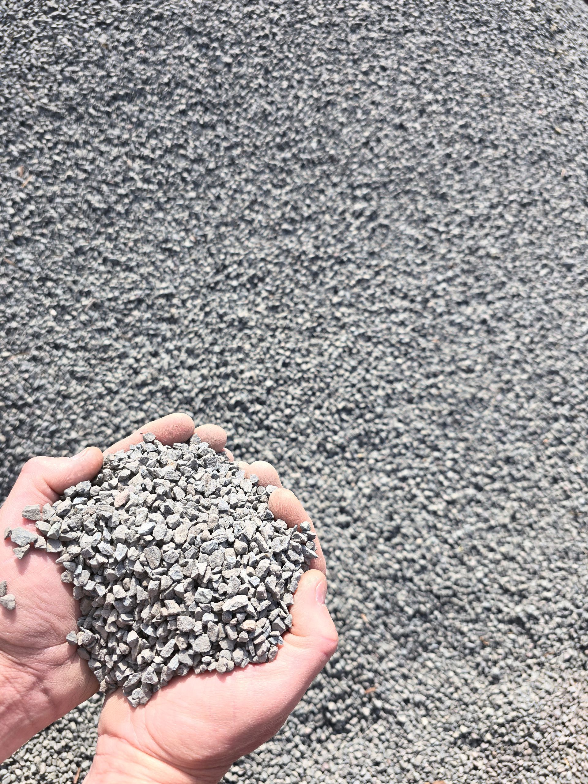 Hands Holding a Pile of Grey Gravel — BVN Landscape and Concrete Supplies in Sussex Inlet, NSW