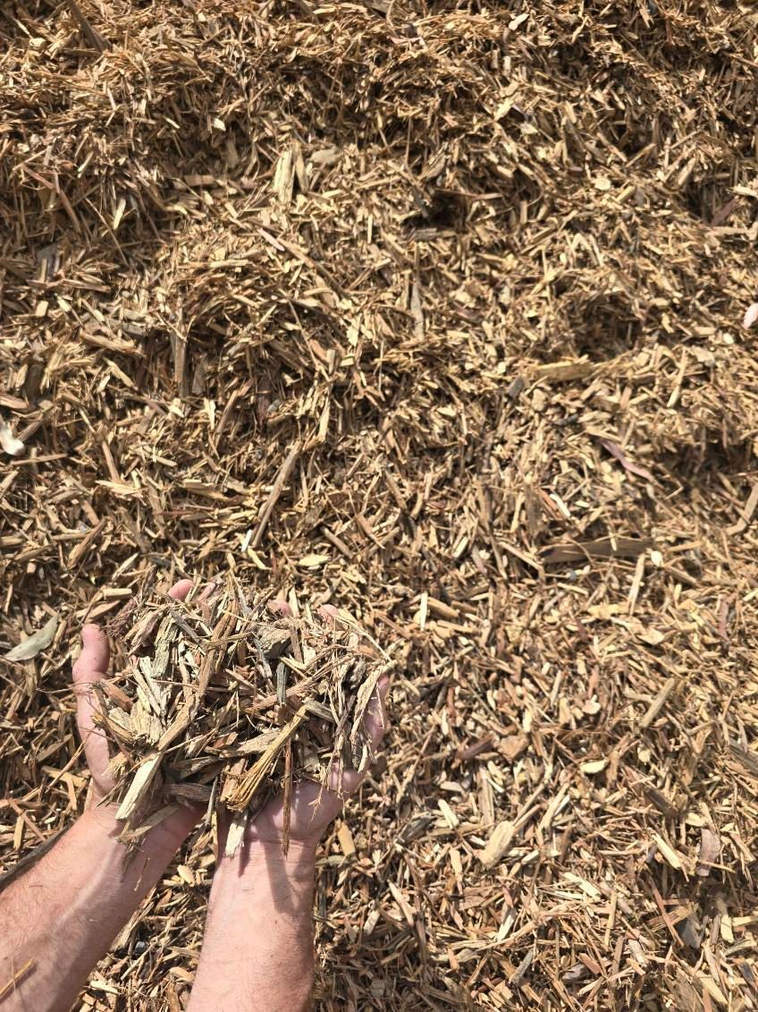 Hands Holding a Pile of Light Brown Wood Chips — BVN Landscape and Concrete Supplies in Nowra, NSW