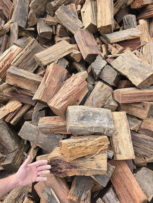 A Person 's Hand Is Reaching out Towards a Pile of Wood — BVN Landscape and Concrete Supplies in St Georges Basin, NSW