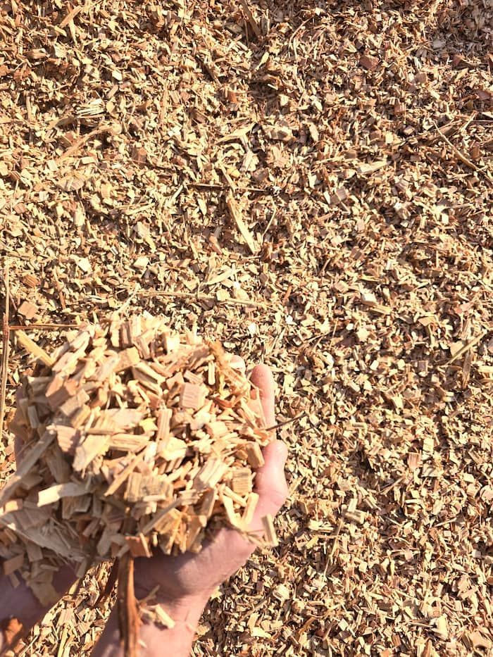 A Person Is Holding a Pile of Wood Chips in Their Hand — BVN Landscape and Concrete Supplies in St Georges Basin, NSW