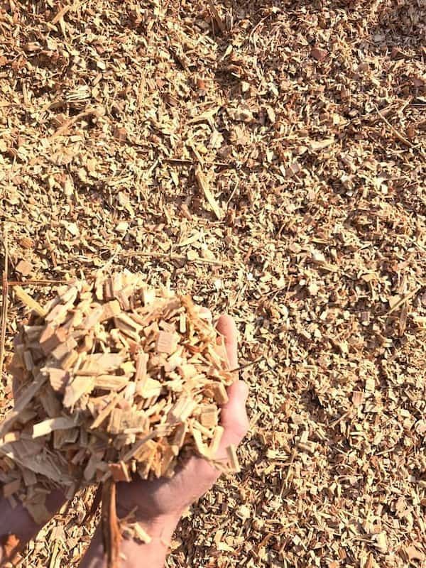 A Person Is Holding a Pile of Wood Chips in Their Hand — BVN Landscape and Concrete Supplies in St Georges Basin, NSW