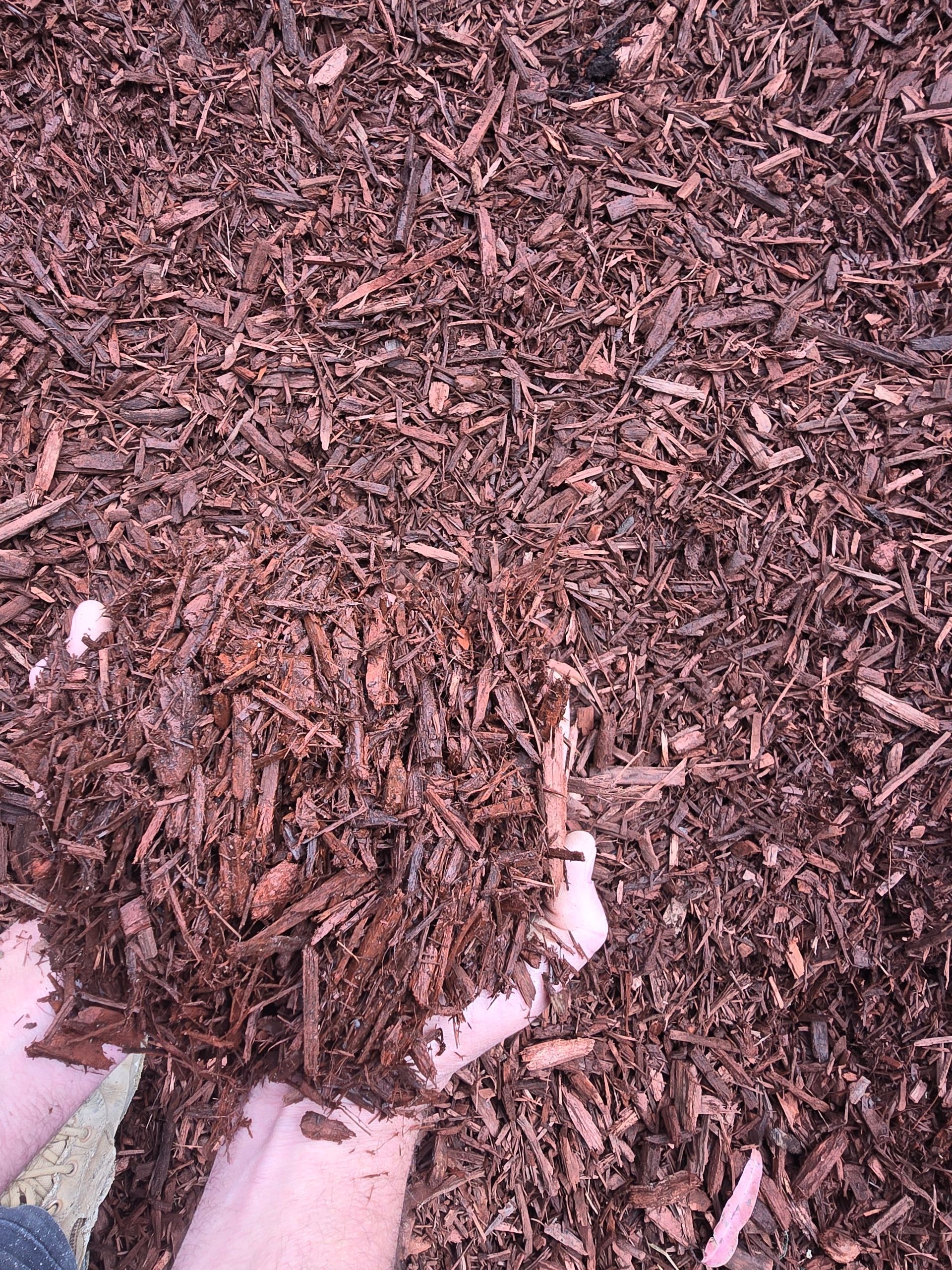 Hands Holding Dark Brown Mulch — BVN Landscape and Concrete Supplies in St Georges Basin, NSW