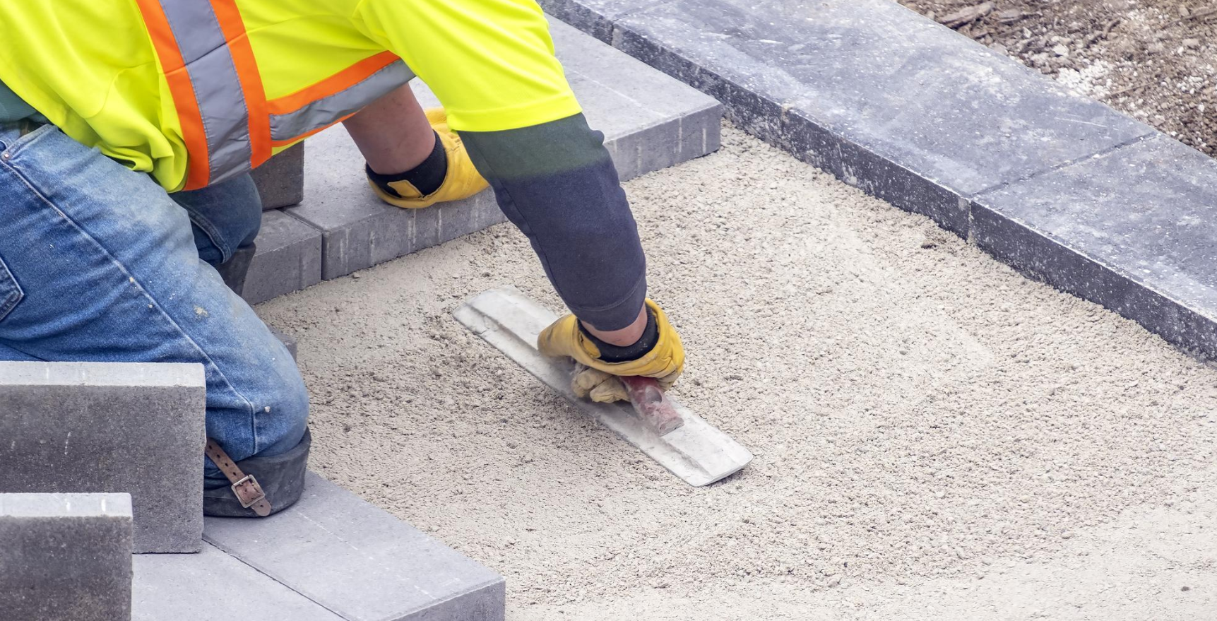 A Construction Worker Is Kneeling Down On A Construction Site — BVN Landscape and Concrete Supplies in St Georges Basin, NSW