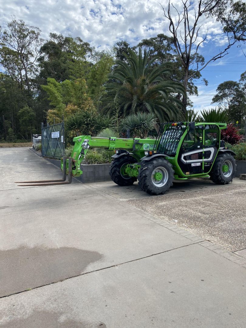 Green Telehandler With Extended Forks on Pavement — BVN Landscape and Concrete Supplies in St Georges Basin, NSW