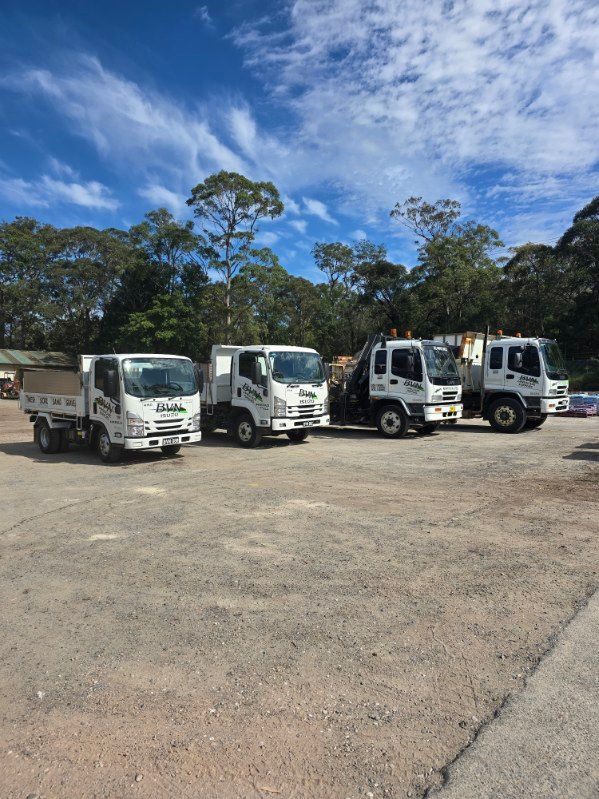 Five White Work Trucks Parked on a Gravel Lot — BVN Landscape and Concrete Supplies in Ulladulla, NSW