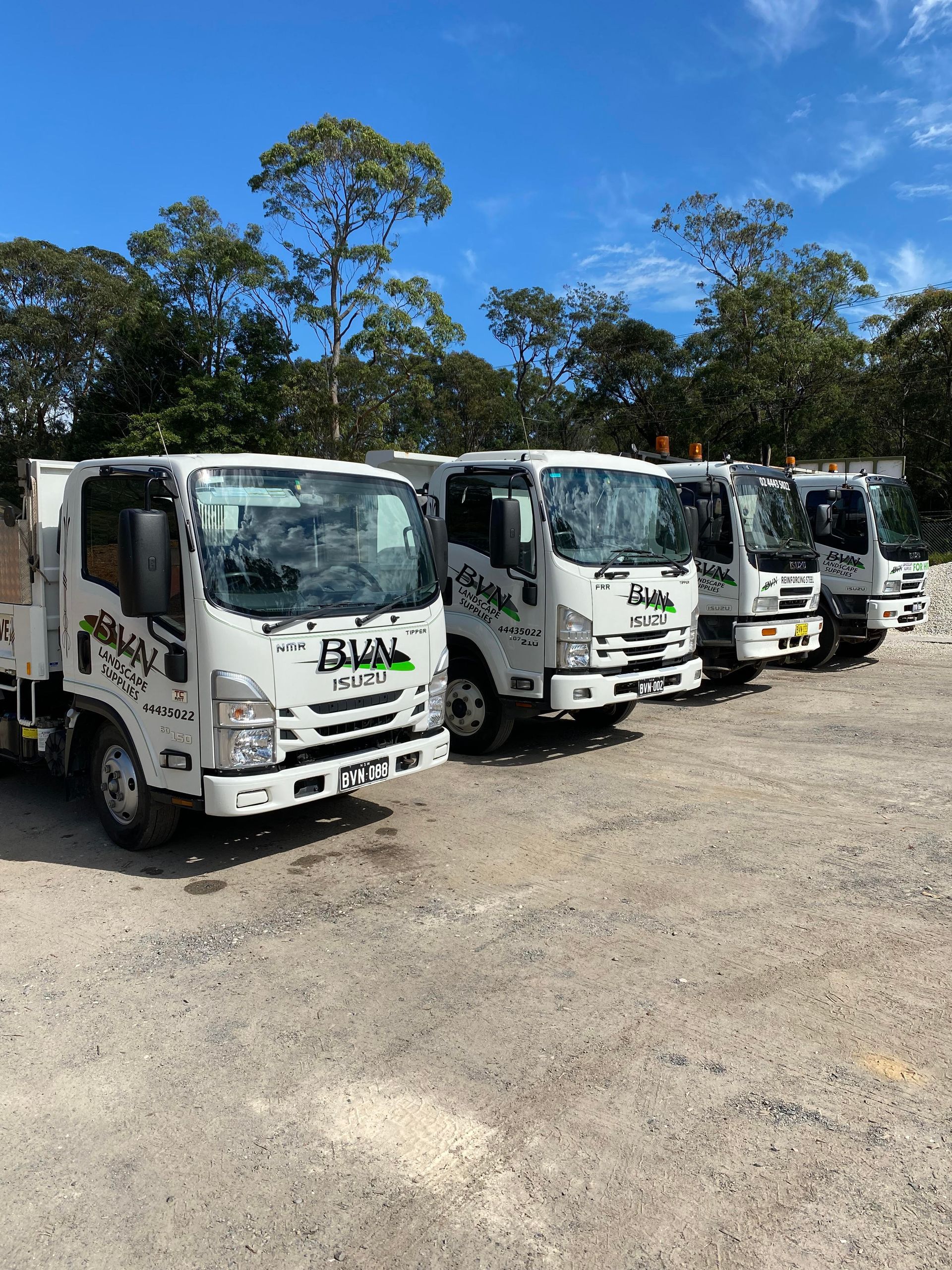 Five White Isuzu Trucks Lined Up on Gravel, Under a Blue Sky — BVN Landscape and Concrete Supplies in St Georges Basin, NSW