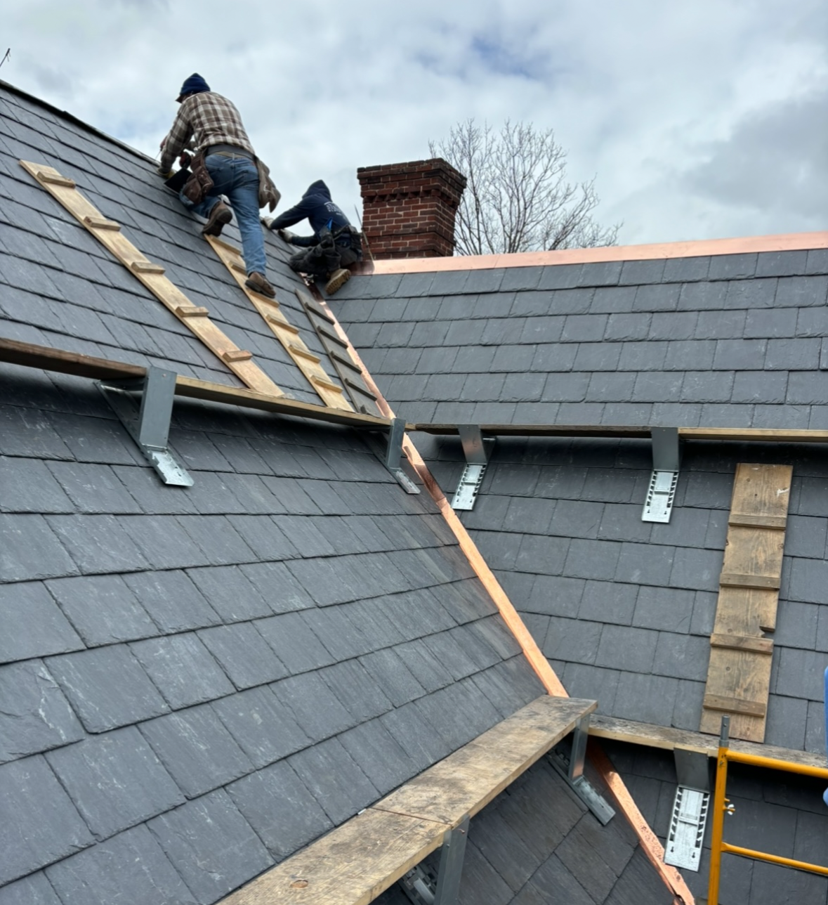 Two men are working on the roof of a house
