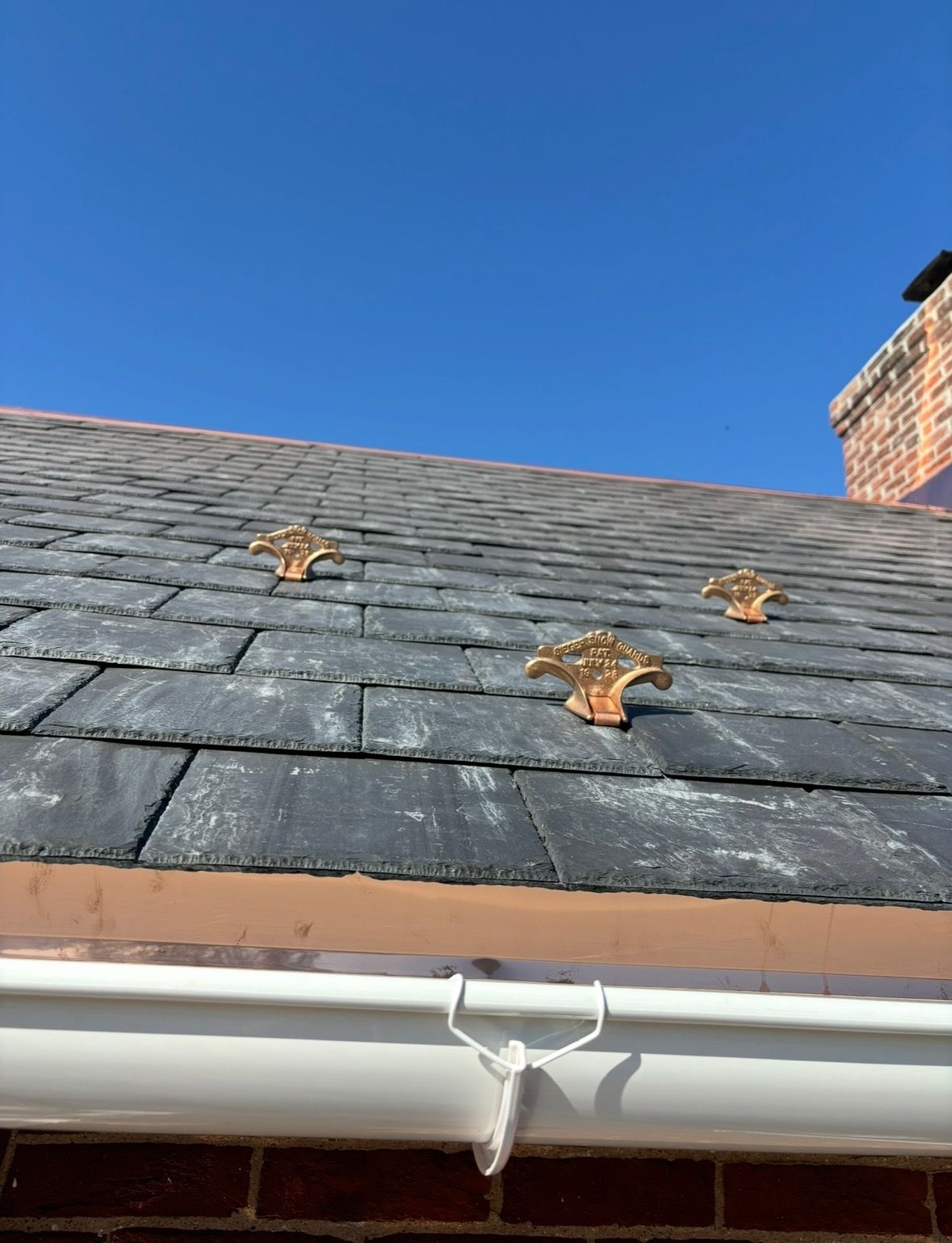 A roof with a white gutter and a blue sky in the background.
