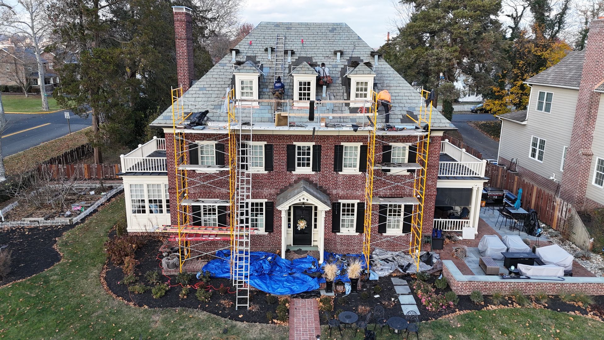 An aerial view of a large brick house being remodeled.