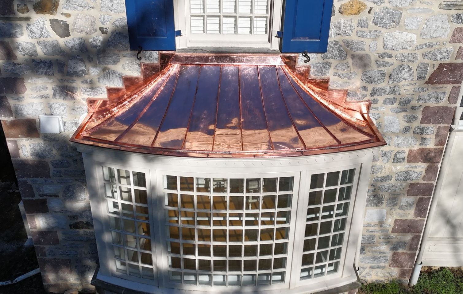 A white house with a copper roof and a window
