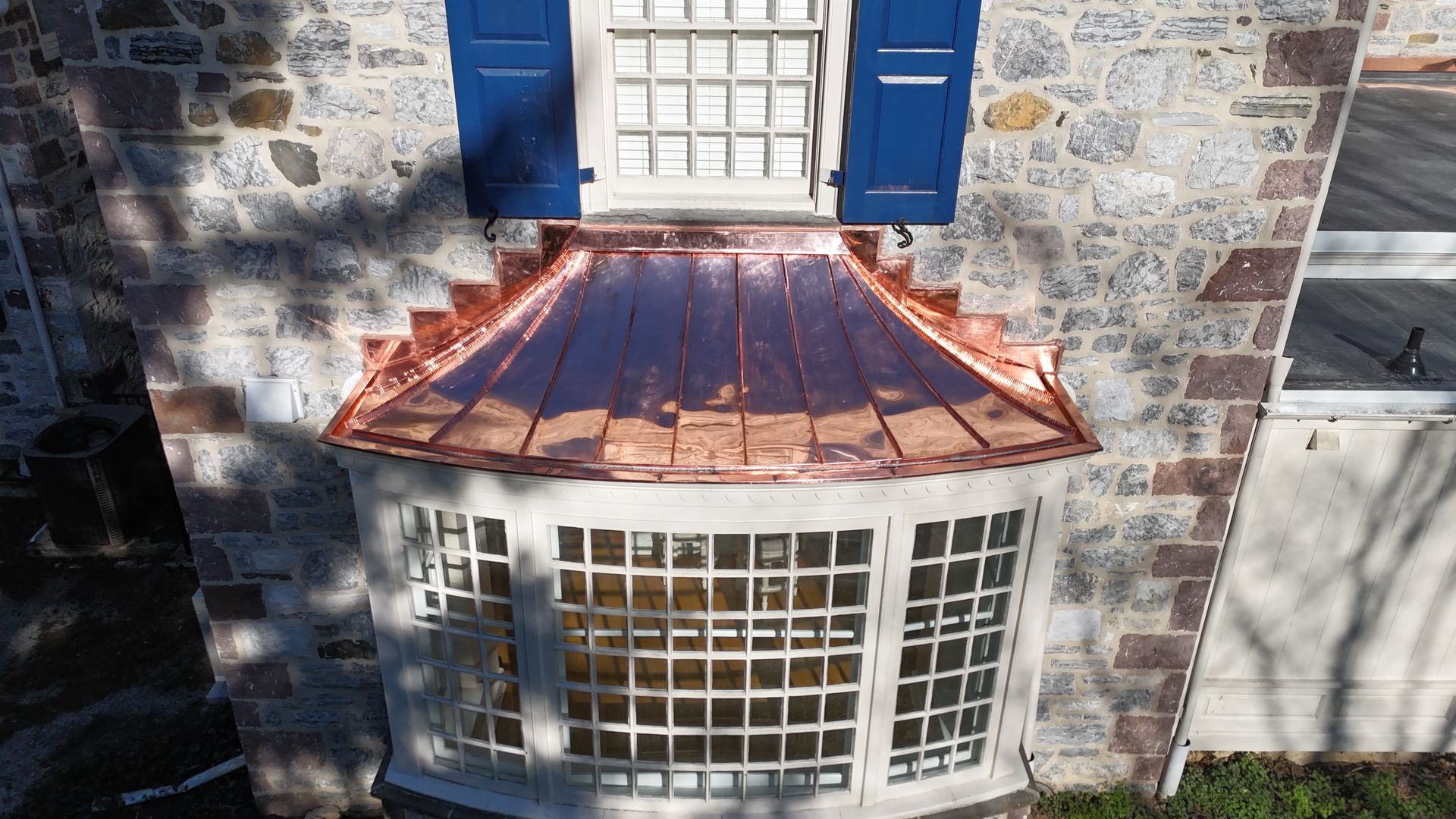 A white brick house with a copper gutter on the side of it.